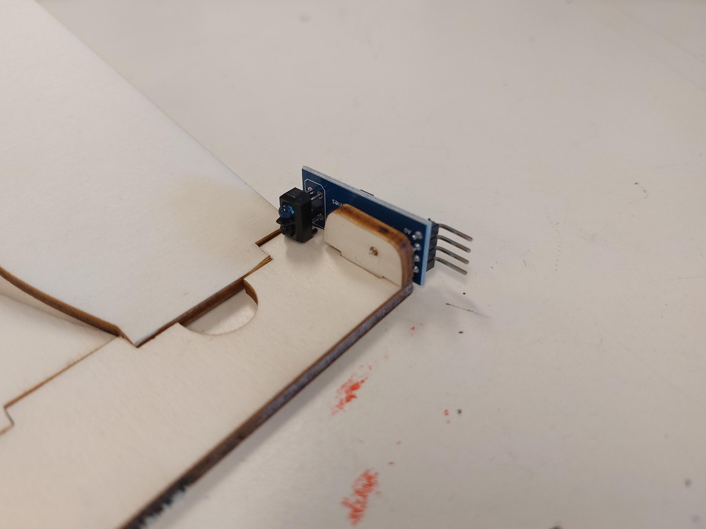 De blauwe infraroodsensor zit aan de voorkant van de houten baan.