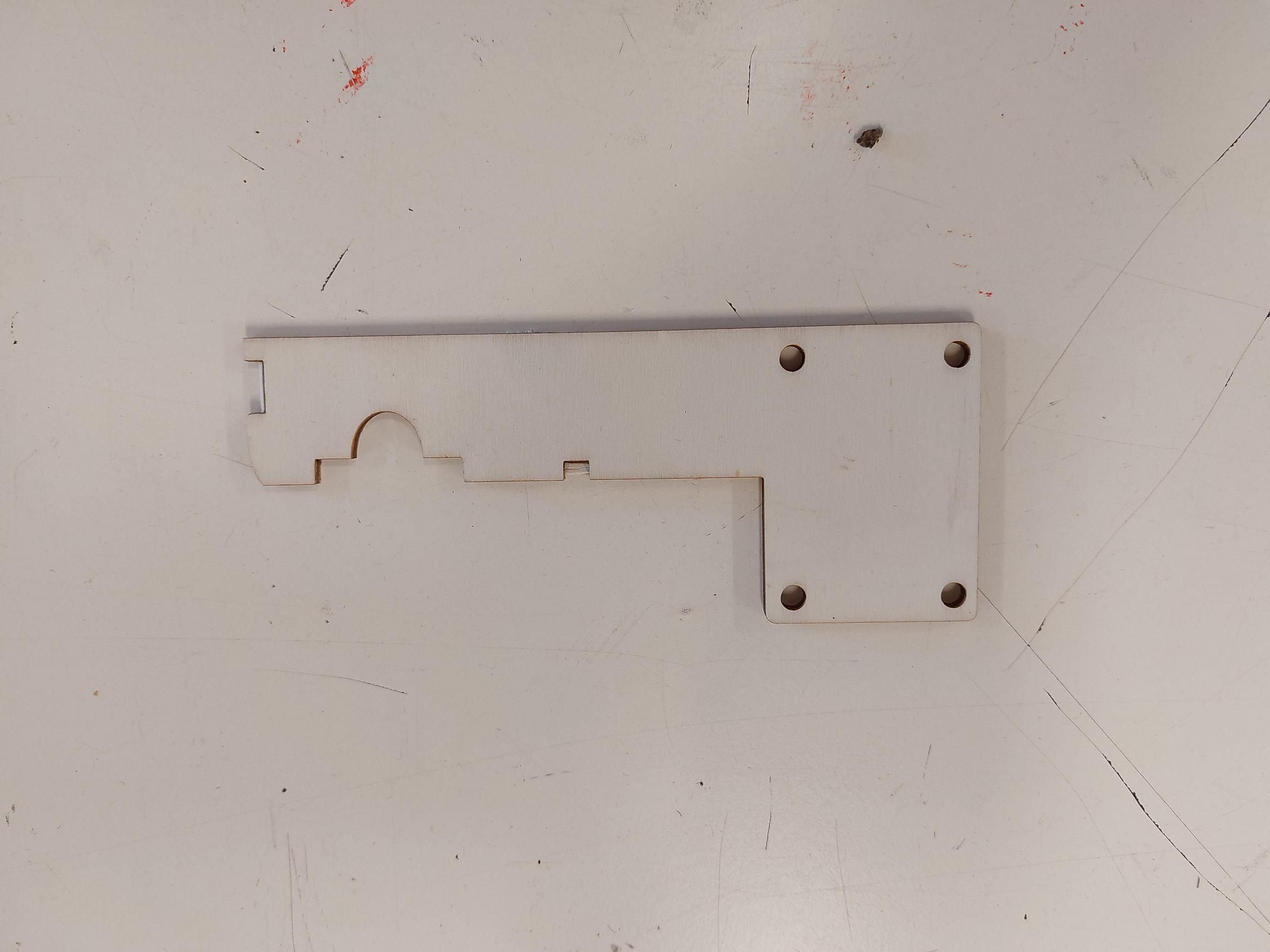 De houten bodemplaat met vier schroefgaten in de hoeken.